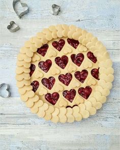 a pie with hearts cut out of it sitting on top of a white wooden table