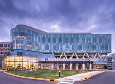 a large glass building sitting on the side of a road next to a parking lot