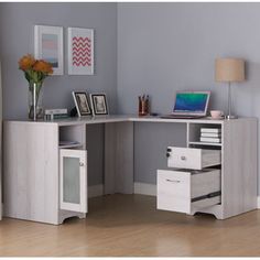 a corner desk with drawers and a laptop on it