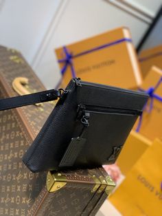 a small black purse sitting on top of a piece of luggage next to other boxes