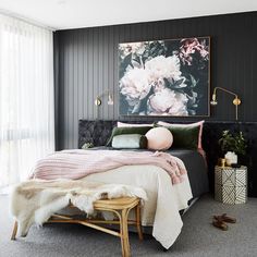 a black and white bedroom with pink flowers on the wall above the bed, along with an ottoman