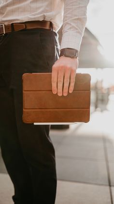 a man holding a brown briefcase on his left hand while wearing a dress shirt and slacks