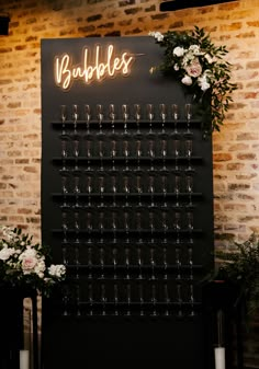 a wall mounted wine glass rack with candles and flowers on it in front of a brick wall