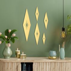 a table with candles, vases and flowers on it in front of a green wall