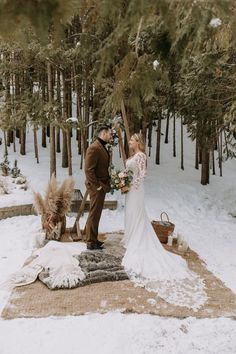 a bride and groom are standing in the snow near some pine trees with their dog