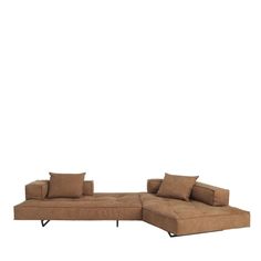 a brown sectional couch with pillows on it's back and arms, in front of a white background