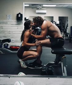 a man kneeling down next to a woman in a gym