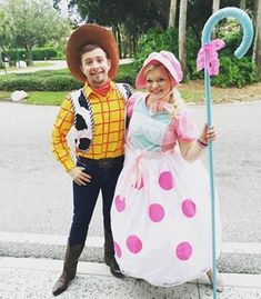 a man and woman in costume standing next to each other on the side of the road