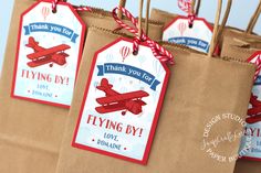 some brown paper bags with red and blue tags hanging from it's handles that say, thank you for flying by