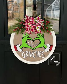 the grinches door hanger is decorated with red bows and green hands holding a heart