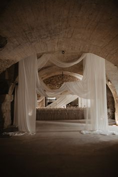 an empty room with white drapes on the ceiling