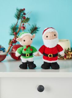 two knitted santa and mrs claus dolls standing next to each other on a table