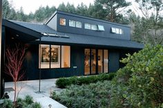 a black house surrounded by trees and bushes