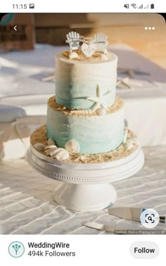 a three tiered wedding cake with shells and starfish on the top, sitting on a table