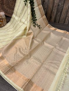 -Classic cream Kanjivaram saree with a striped zari pattern and heavy zari palla. -Pure silk saree authenticated by Silk Mark Certificate. -Blouse fabric included. -Fall attached. Note:  - Slight inconsistency in weaving is inherent to handloom sarees and is not a defect. -The color of the products may slightly vary according to the ambient lighting conditions and the color calibration of LED devices. If you would like more clarity before your purchase, please drop us a message . Festive Cream Slub Silk Traditional Wear, Cream Slub Silk Dupatta With Zari Work, Cream Slub Silk Dupatta For Diwali, Cream Pre-draped Saree With Cutdana For Diwali, Cream Cutdana Pre-draped Saree For Diwali, Gold Art Silk Pre-draped Saree With Border, Bollywood Style Gold Pre-draped Saree With Border, Festive Cream Saree With Cutdana, Cream Raw Silk Saree