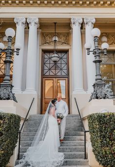 a bride and groom standing on the steps of a building