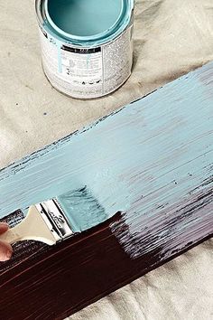 someone is painting the wood with blue paint