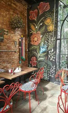 the interior of a restaurant with painted walls and red chairs, tables and stools