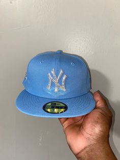 the new york yankees hat is being held up by a man's hand in front of a white wall