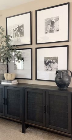 a living room with pictures on the wall and a vase sitting on top of it