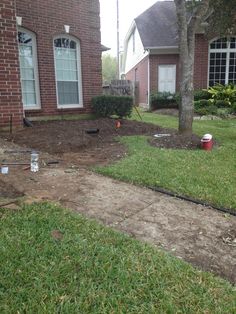 a yard with grass and dirt in front of a brick house