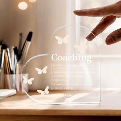 a clear acrylic plaque with the words coaching and butterflies on it in front of a desk