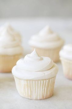 cupcakes with white frosting sitting on a table