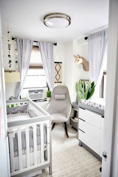 a baby's room with a chair, crib and desk in it is shown