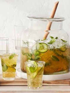 a pitcher filled with ice and cucumbers next to two glasses full of water