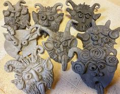 five different masks are sitting on the floor next to each other and one is made out of clay