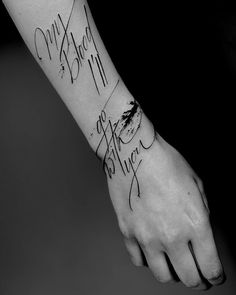 a black and white photo of a person's wrist with writing on it