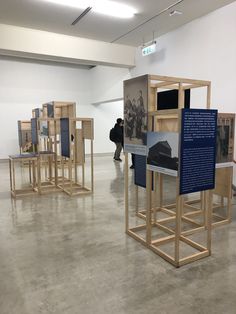 a group of wooden structures in a room with people walking around them and pictures on the walls