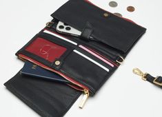 Transition seamlessly from a wallet to a clutch or crossbody thanks to Levy's removable, adjustable strap. Even when you wear Levy on your shoulder, it's packed with all the organizational elements of your favorite wallet, from four credit card slots and two bill drop pockets to a clear ID slot and cell phone pocket. Crafted with classic black leather Red logo twill lining Brushed gold hardware, guaranteed for life Removable adjustable cross body strap Magnetized flap closure and two zippered po Chic Travel Wallet On Chain With Card Slots, Travel Wallet Clutch With Detachable Chain Strap, Brushed Gold Hardware, Red Logo, Luxury Handbags, Red Gold, Gold Hardware, Cross Body, Classic Black