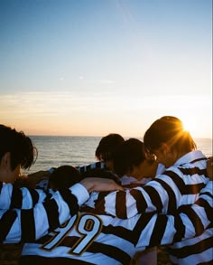 a group of young people standing next to each other on top of a sandy beach