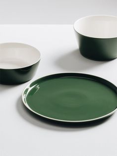 two green and white plates sitting on top of a table next to each other in front of a bowl