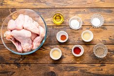 ingredients for chicken wings laid out in bowls on a wooden table, including garlic and seasonings