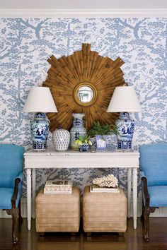 a white table topped with blue and white vases next to a wall mounted mirror