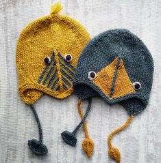 two knitted hats with eyes and ears are laying on a white surface next to each other