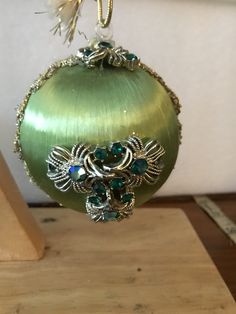 a green ornament hanging from a wooden stand