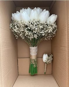 a bouquet of white tulips and baby's breath in a cardboard box