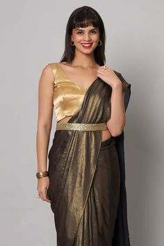 Unveil the allure of our Meera Dark Grey & Gold Shimmer Georgette One Minute Saree. In shades of Dark Grey & Gold, this saree is pure elegance. The Gold Shimmer adds a celestial touch, while the Pallu dances with the grace of shell tassel lace. Accompanied by a Comfort stretch Gold tie blouse, this outfit is your ticket to red-carpet glow. About this Product Saree: Saree Color: Dark Grey with Gold Saree Fabric: Georgette Type of Work: Gold Shimmer Trims: Pallu border shell Tassel Lace Drape Styl Elegant V-neck Georgette Pre-draped Saree, Elegant V-neck Pre-draped Georgette Saree, V-neck Saree With Pallu For Reception, Reception Saree With V-neck Pallu, V-neck Reception Saree With Pallu, Elegant Chanderi Pre-draped Saree For Evening, Festive Pre-draped V-neck Saree With Unstitched Blouse, Traditional V-neck Pre-draped Saree For Parties, Elegant Lehenga With Zari Work And V-neck