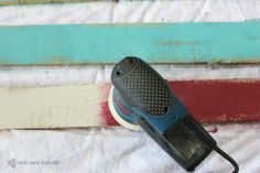 an electric sanding machine sitting on top of a white towel covered floor next to a colorful wall