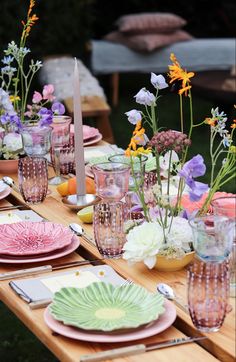 a long table with plates and flowers in vases sitting on top of each other