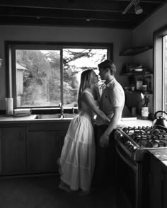 a man and woman standing next to each other in front of a stove top oven