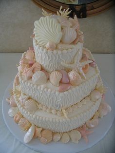 a three tiered wedding cake with seashells on it