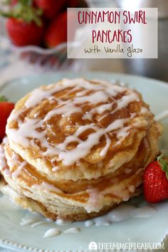 cinnamon swirl pancakes with vanilla glaze on a white plate next to some strawberries