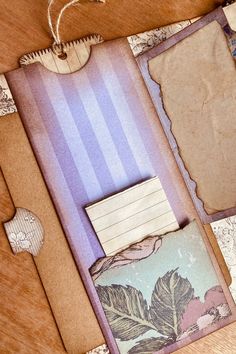 an open book with some papers attached to it on top of a wooden table next to other items