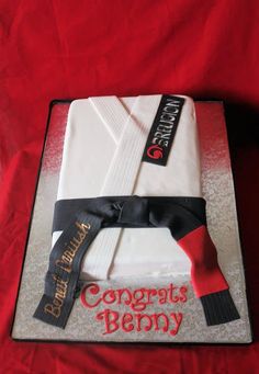 a cake that is on top of a red cloth covered table with a black and white ribbon