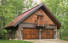 a house with two garages in front of it and trees around the driveway area