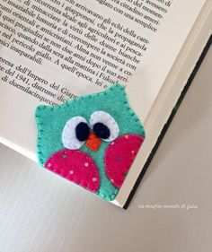 an owl bookmark made out of felt sits on top of the open page of a book